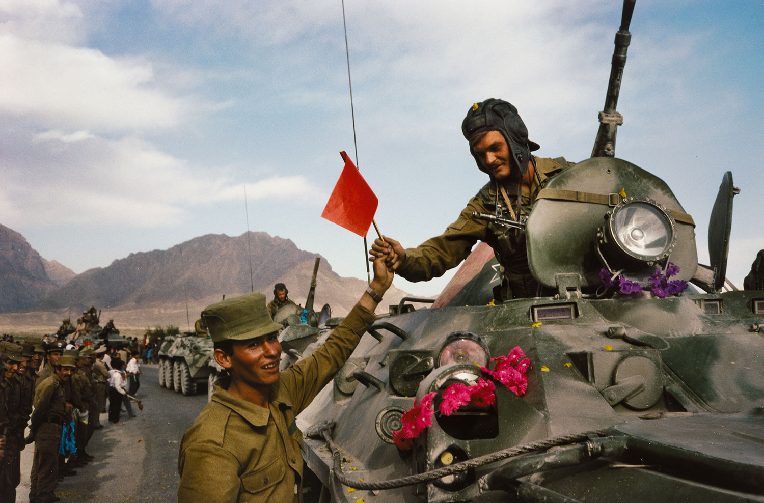 <An Afghan soldier hands a flag in solidarity to a departing Soviet soldier in Kabul, 1988, 